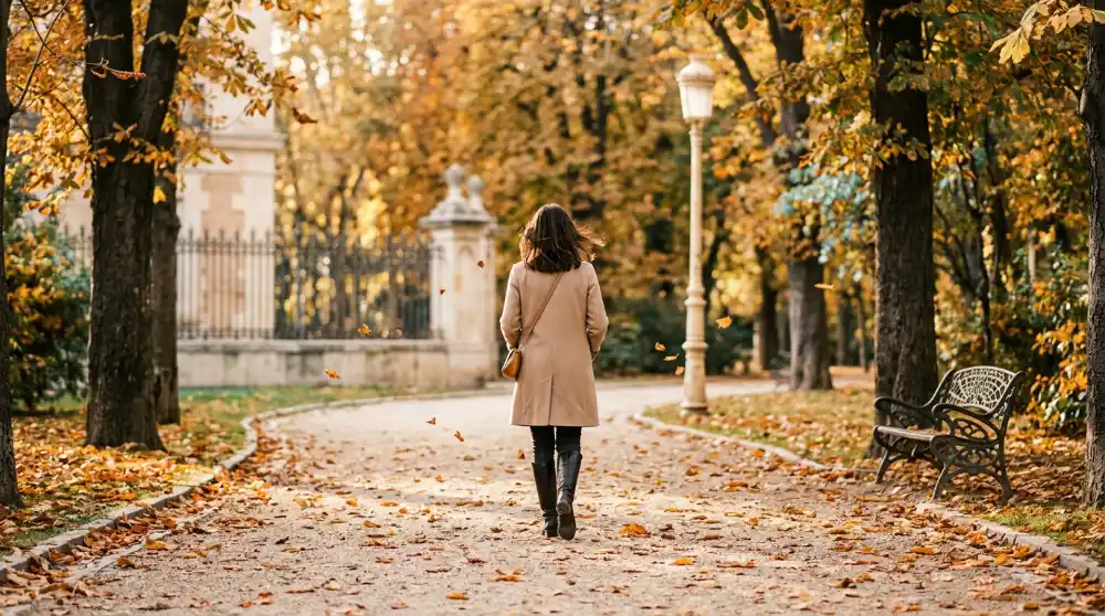 Mujer paseando por un parque con hojas de otoño